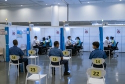 FILE - Members of the Hong Kong Fire Services Department receive a dose of the Sinovac Biotech's COVID-19 vaccine at a community vaccination center in Hong Kong, China, Feb. 23, 2021. (Paul Yeung/Pool via Reuters)
