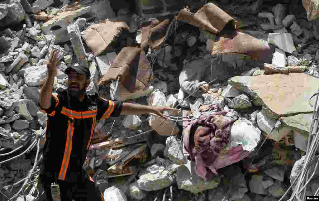 Un trabajador de rescate palestino gesticula junto a una víctima entre los escombros en el lugar de los ataques aéreos israelíes, en la ciudad de Gaza.