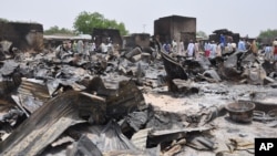 FILE - People stand outside burned houses following an attack by Islamic militants in Gambaru, a city in Nigeria's Borno state, May 11, 2014.