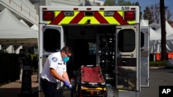 An EMT disinfects a gurney after transporting a patient at St. Joseph Hospital in Orange, Calif., Jan. 7, 2021. California health authorities reported Thursday a record two-day total of 1,042 coronavirus deaths.