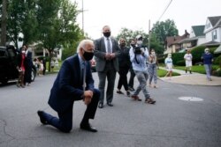 Democratic presidential candidate Joe Biden kneels to talk with a child during a visit to Biden's childhood home in Scranton, Pa., July 9, 2020.