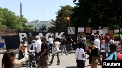 People gather to view protest signs now affixed to the fence around Lafayette Square at the scene where protesters clashed with police, near the White House in Washington, June 8, 2020.