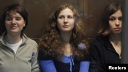 Members of the female punk band "Pussy Riot" (L-R) Yekaterina Samutsevich, Maria Alyokhina and Nadezhda Tolokonnikova sit in a glass-walled cage before a court hearing in Moscow, October 10, 2012. 