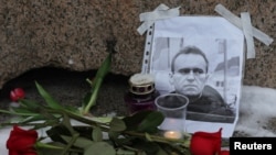 Bunga ditempatkan di samping potret pemimpin oposisi Rusia Alexey Navalny di monumen para korban penindasan politik setelah kematian Navalny, di Saint Petersburg, Rusia 16 Februari 2024. (REUTERS/Stringer)