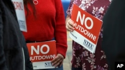 FILE - People protest the partial government shutdown in downtown Denver, Colorado, Jan. 10, 2019. Some federal workers are taking second jobs to stay afloat.