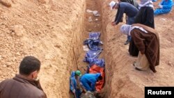 FILE - Men excavate remains of more than 25 men reportedly killed by Islamic State fighters on the outskirts of Saadia in Iraq's Diyala province, Jan. 15, 2015. 