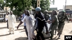 Security forces use a blanket to transport the remains of some of the 11 victims of a double blast in the northern Cameroonian city of Maroua, July 22, 2015. 