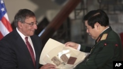 U.S. Defense Secretary Leon Panetta, left, gives a Vietnam War memorabilia of a Vietnamese soldier to his counterpart Phung Quang Thanh in Hanoi, Vietnam, June 4, 2012.