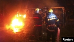 Nhân viên cứu hỏa cố gắng dập tắt một chiếc xe cảnh sát bị đốt cháy ở thành phố Lô Châu, tỉnh Tứ Xuyên, ngày 17/10/2012