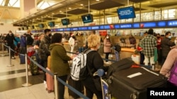 Passengers line up at John F. Kennedy International Airport after airlines announced numerous flights were canceled during the spread of the Omicron coronavirus variant on Christmas Eve in New York, Dec. 24, 2021.