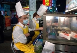 Two vendors wear face masks and wait for customers at a night market in Taipei, Taiwan, Thursday, Feb. 6, 2020.