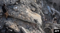 গাজা সিটির দক্ষিণে ইসরায়েলি হামলার পর একটি ভবনের ধ্বংসাবশেষ দেখছে ফিলিস্তিনিরা। ফটোঃ ২২ নভেম্বর, ২০২৪।