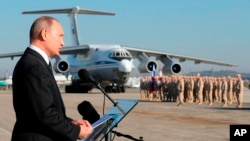 FILE - In this Dec. 12, 2017 file photo, Russian President Vladimir Putin addresses the troops at the Hemeimeem air base in Syria.