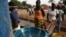 Girls fill plastic basins at a free water tap in a neighborhood where houses with indoor plumbing rarely receive water, in Bissau, Guinea-Bissau, March 6, 2009. Contaminated drinking water leads to yearly cholera epidemics, particularly in remote rural re