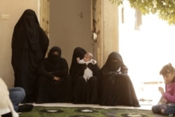 FILE - Women who recently returned from the Al-Hol camp, which holds families of Islamic State members, gather in the courtyard of their home in Raqqa, Syria, during an interview, Sept. 7, 2019.