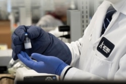 FILE - A sample of a vaccine for the novel coronavirus (COVID-19) is displayed at a laboratory in San Diego, California, March 17, 2020. H-1B visas cover highly skilled occupations that require at least a bachelor’s degree or equivalent.