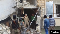FILE - A civil defense member gestures toward a rebel fighter as they search for survivors at a site hit by what activists said were airstrikes carried out by the Russian Air Force in Idlib, Syria, Dec. 20, 2015.