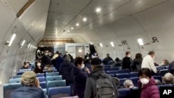 Waga AS yang dievakuasi dari karantina kapal pesiar Diamond Princess, memasuki pesawat Kalitta di bandara Haneda, Tpkyo, menuju Amerika. (Foto: Cheryl dan Paul Molesky via AP). 