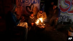 FILE -- In this Jan. 25, 2016 file photo, Palestinians, who get only several hours of electricity a day, sit around a fire outside their home in Gaza City. Israel said Thursday, April 27, 2017, that it was informed that the Palestinian self-rule government in the West Bank will stop paying for electricity Israel sells to the Gaza Strip.