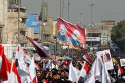 Iraqis, including supporters of Hashid Shaabi (Popular Mobilization Forces), hold flags and placards depicting senior Iranian military commander General Qassem Soleimani and Iraqi militia commander Abu Mahdi al-Muhandis, in Baghdad, Jan. 3, 2021.