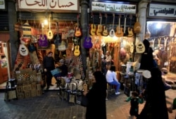 FILE - People walk past shops in al-Hamidieh Souk in Damascus, Syria, April 15, 2018.
