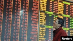 An investor looks at an electronic board showing stock information at a brokerage house in Hangzhou, Zhejiang province, China, December 14, 2012. 