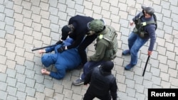 Unidentified people, who are presumably Belarusian law enforcement officers, restrain a man during a rally to reject the presidential election results in Minsk, Belarus, Nov. 8, 2020. 