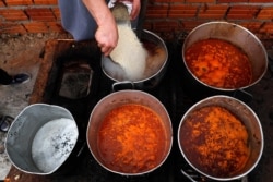 FILE - Chef Walter Ferreira pours rice into a stew at a soup kitchen in Luque, Paraguay, May 11, 2020. The number of soup kitchens in the country has increased, as the country's economy grinds down due to the new coronavirus pandemic lockdown.