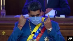 Venezuelan President Nicolás Maduro removes his mask as he prepares to speak about his annual report to the nation before legislators in the National Assembly, Caracas, Jan. 12, 2021.