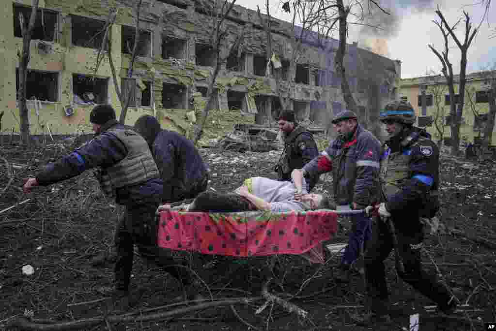 Ukrainian emergency employees and volunteers carry an injured pregnant woman from the damaged by Russian shelling a maternity hospital in Mariupol, March 9, 2022.