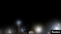 Masked pro-democracy protesters hold up their phones during a rally in Tsim Sha Tsui district, Hong Kong, Oct. 5, 2019. 