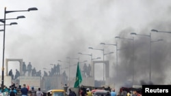 Demonstrators stand in front of Iraqi security forces at Al Jumariyah Bridge during a protest over corruption, lack of jobs, and poor services, in Baghdad, Oct. 27, 2019.