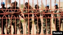 FILE - United Nations peacekeepers from Senegal peer from behind a gate in Gao, Mali, during a protest against sending them to the northern rebel-held town of Kidal, July 5, 2013.