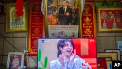 FILE - A television shows a broadcast of a Chinese talk show program as it sits beneath a photo of Chinese President Xi Jinping in a home converted into a tourist homestay in Zhaxigang village in western China's Tibet Autonomous Region, June 4, 2021.