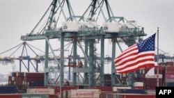 Кинески транспортни контејнери покрај знамето на САД откако беа истоварени во пристаништето Лос Анџелес во Калифорнија, 14 мај 2019 година