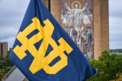 FILE - A Notre Dame monogram flag waves in front of the Word of Life mural on the campus of the University of Notre Dame, in South Bend, Indiana, Sept. 28, 2019.