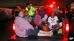 Residents ride in the bed of an emergency vehicle carrying them to safety following flooding to their homes late Monday night, Aug. 28, 2017 in Lake Charles, La.