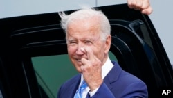 US President Joe Biden crosses his fingers as he responds to a question about the short-term debt deal as he arrives Air Force One at O'Hare International Airport in Chicago, Oct. 7, 2021. 