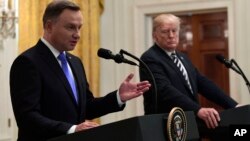 President Donald Trump, right, listens as Polish President Andrzej Duda, left, speaks during a joint news conference in the East Room of the White House in Washington, Sept. 18, 2018. 