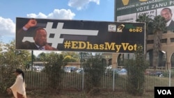A citizen walks past a poster of President Emmerson Mnangagwa at the ZANU-PF party headquarters in Harare, June 25, 2018. Mnangagwa says the country is safe and stable to conduct elections on July 30 despite an explosion at a rally he addressed over the weekend.