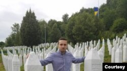 Behidin Piric, a survivor of the Srebrenica Genocide of 1995, stands next to the graves of his grandfather and great-uncles, who were killed in the massacre,while visiting the Srebrenica Memorial Center in Bosnia in 2019. 