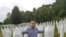 Behidin Piric, a survivor of the Srebrenica Genocide of 1995, stands next to the graves of his grandfather and great-uncles, who were killed in the massacre,while visiting the Srebrenica Memorial Center in Bosnia in 2019. 