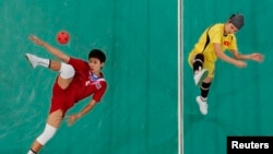 FILE - Thailand's Tidawan Daosakul (red) plays the ball against Vietnam's Nguyen Hai Thiao during their women's sepak takraw regu final at the 2010 Asian Games.