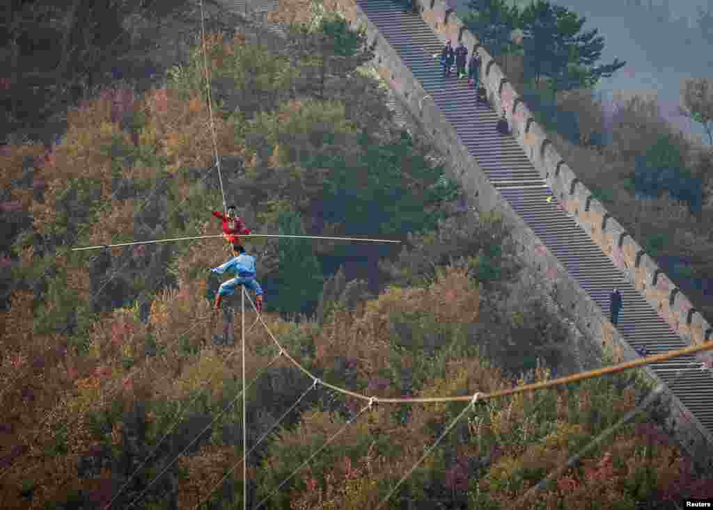 Adili Wuxor (berbaju merah) yang dikenal dengan julkan "Pangeran di Atas Tali" menjaga keseimbangannya berjalan meniti tali yang dibentangkan di atas tembok besar di Tianjin, China.