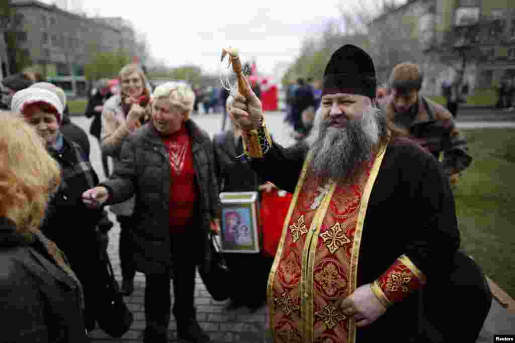 A Ukrainian Orthodox priest sprinkles holy water on worshippers outside a regional government building during Easter in Donetsk, eastern Ukraine, April 20, 2014.&nbsp;