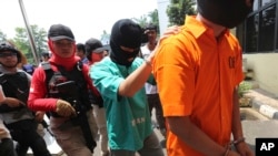 Police escort a suspect involved the making of toxic bootleg alcohol after a press conference in Jakarta, Indonesia, Wednesday, April 11, 2018.