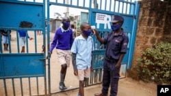 Schoolchildren have their temperature taken as they arrive at the Olympic Primary School in Kibera, one of the capital Nairobi's poorest areas in Kenya, Oct. 12, 2020.