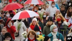 Belarusian women with umbrellas in the colors of the old Belarusian national flag take part in an opposition rally to protest the official presidential election results in Minsk, Belarus, Oct. 24, 2020.