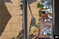 FILE - A Chinese Embassy employee examines broken windows at the embassy after a suicide bombing in Bishkek, Kyrgyzstan, Aug. 30, 2016.
