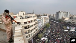 Seorang tentara Iran berjaga dari atas gedung bertingkat, saat berlangsungnya demonstrasi pro-pemerintah di Teheran, Iran, memprotes keras kenaikan harga bahan bakar yang diberlakukan pemerintah, 25 November 2019.